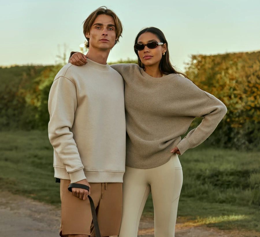 Two people in Now You Live knitwear on a country lane at sunset
