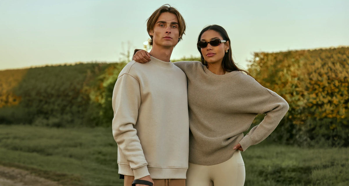 Two people in Now You Live knitwear on a country lane at sunset