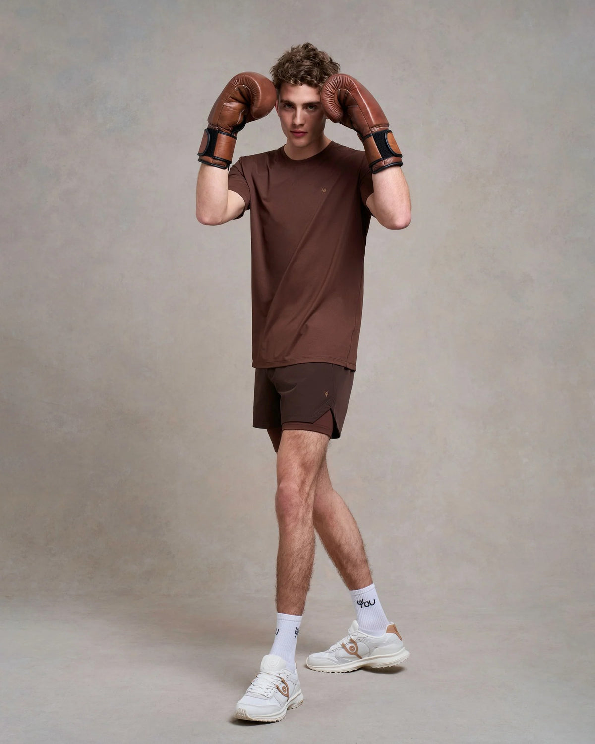 Man in a brown tee and shorts wearing boxing gloves